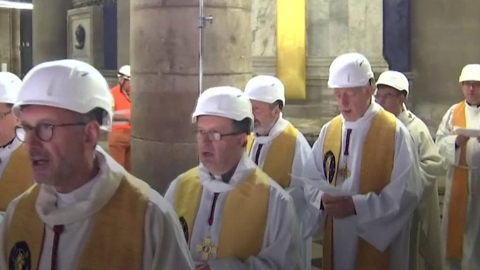 Priests wear hard hats at Notre-Dame