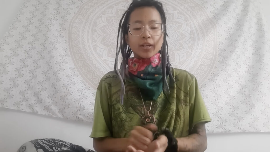 white background of video with asian female with long black hair, wearing green shirt.