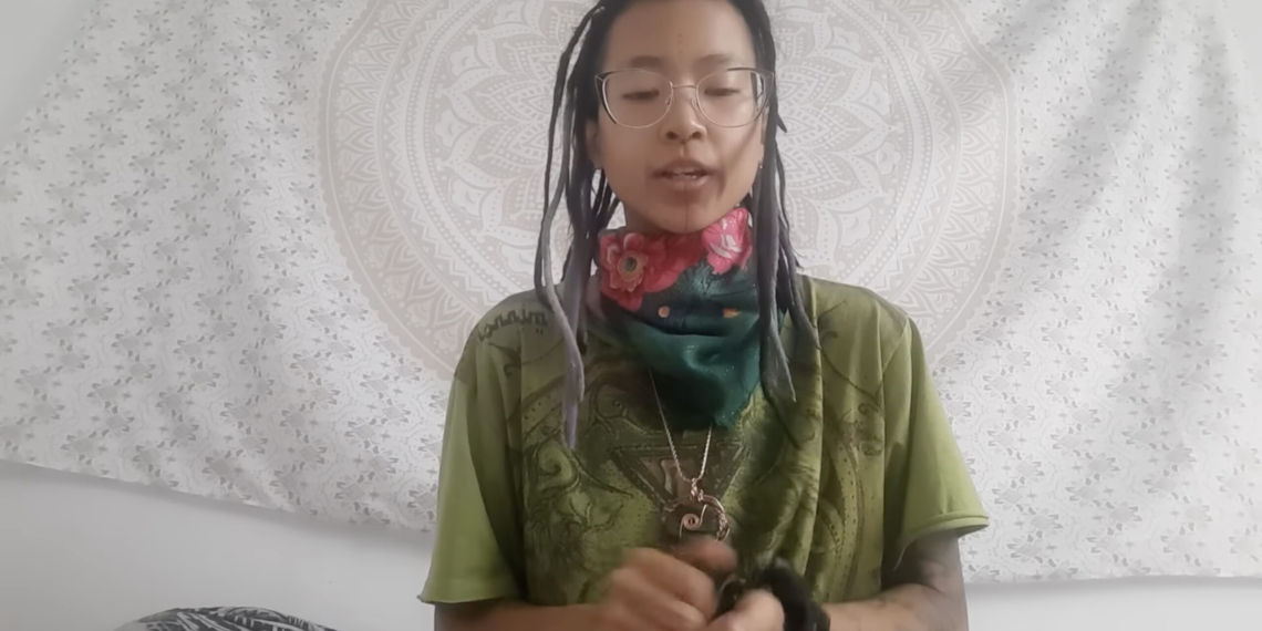 white background of video with asian female with long black hair, wearing green shirt.