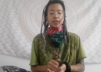 white background of video with asian female with long black hair, wearing green shirt.